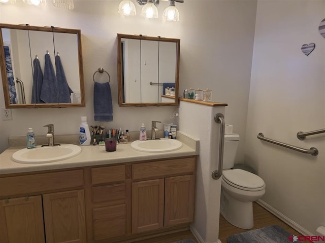 bathroom featuring double vanity, wood finished floors, toilet, and a sink