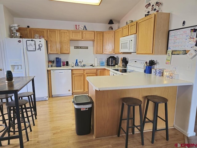 kitchen with light wood-style floors, white appliances, light countertops, and a peninsula