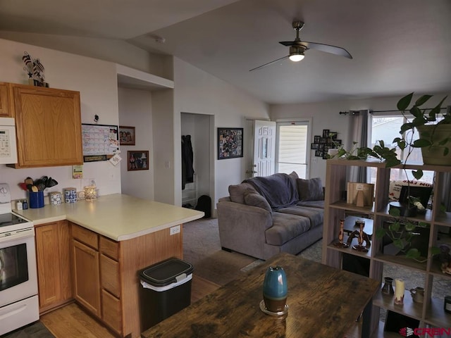 kitchen with open floor plan, light countertops, lofted ceiling, a peninsula, and white appliances