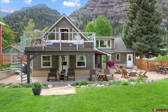 rear view of property featuring a lawn, a patio, fence, an outdoor fire pit, and stairway