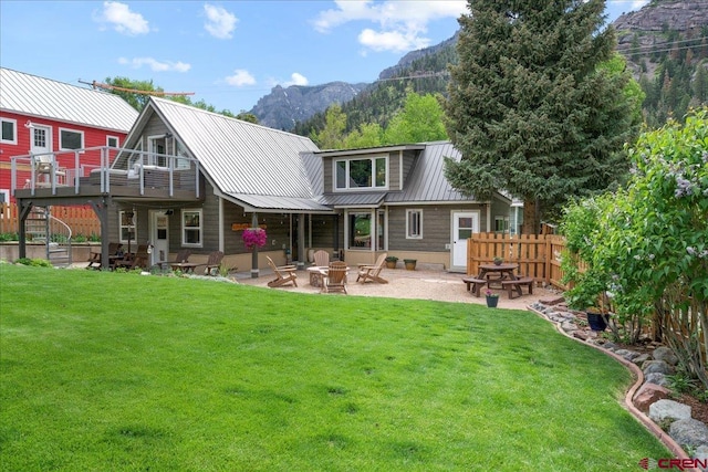 back of house with fence, an outdoor fire pit, a yard, a patio area, and metal roof