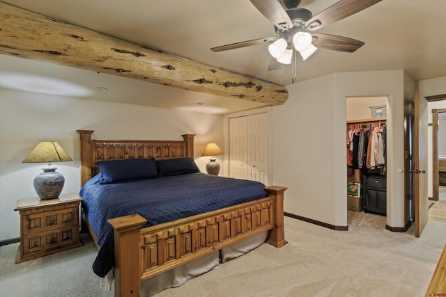 bedroom with a ceiling fan, a walk in closet, light colored carpet, and baseboards