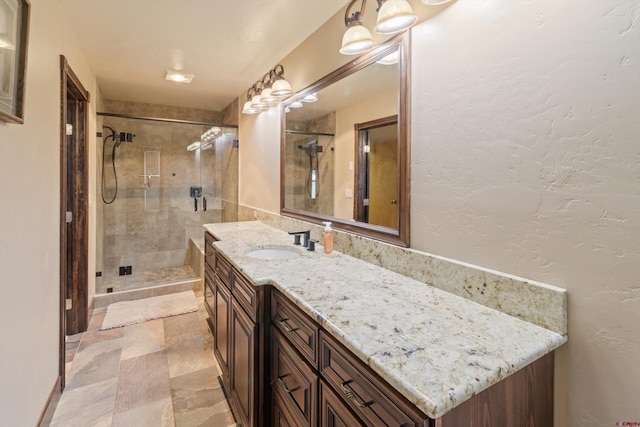 full bath featuring vanity, a shower stall, and stone finish flooring