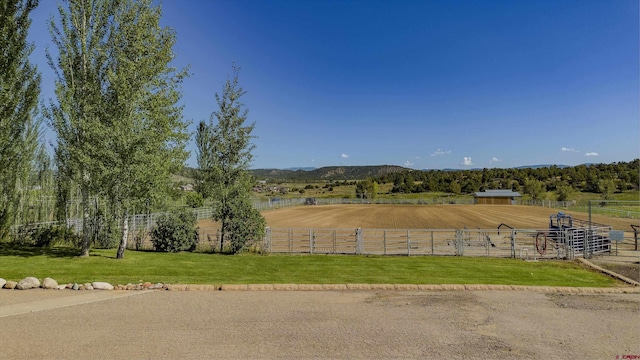 view of yard featuring a mountain view, a rural view, and fence