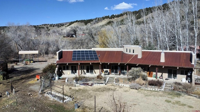 view of front of house featuring metal roof, solar panels, and a mountain view