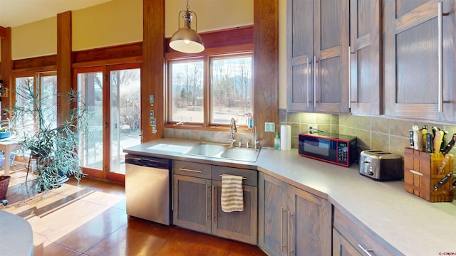 kitchen with backsplash, dishwasher, light countertops, hanging light fixtures, and a sink