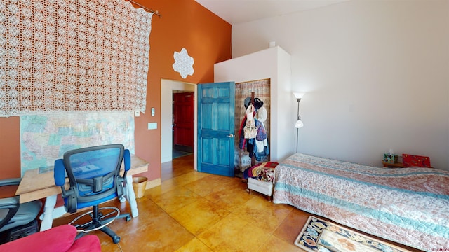 bedroom with a high ceiling and baseboards