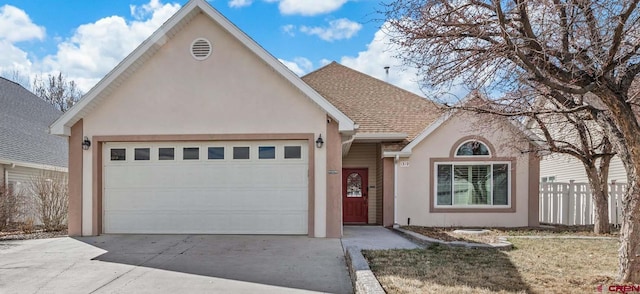 view of front of property featuring a shingled roof, fence, concrete driveway, stucco siding, and an attached garage