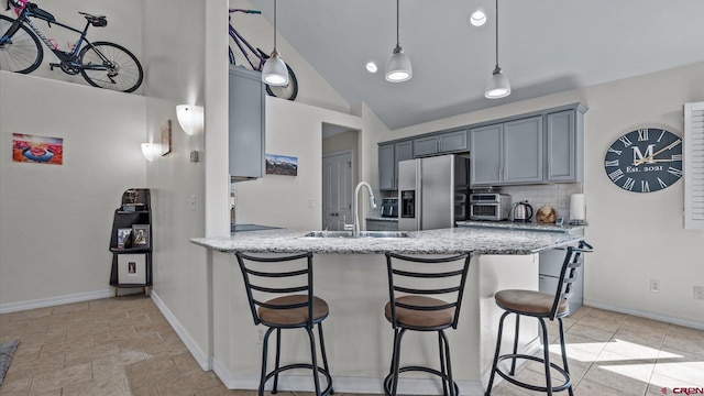 kitchen with backsplash, a kitchen breakfast bar, stainless steel refrigerator with ice dispenser, and a sink