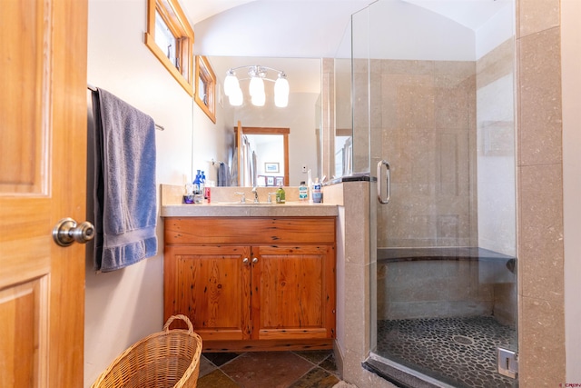 full bathroom with a stall shower, vanity, and vaulted ceiling