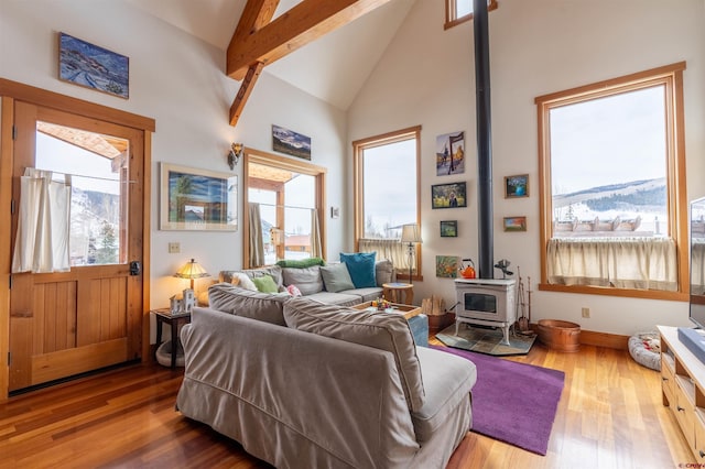 living room with beamed ceiling, high vaulted ceiling, a wood stove, and wood finished floors