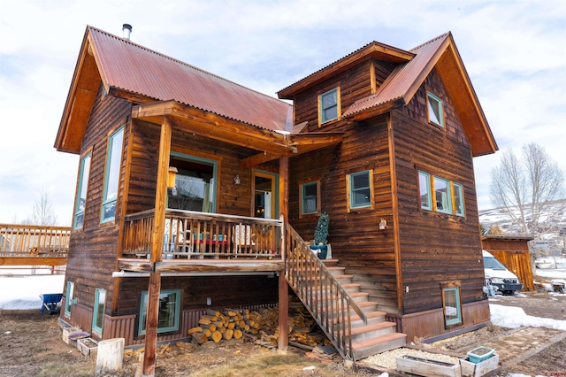 back of house featuring stairway and metal roof