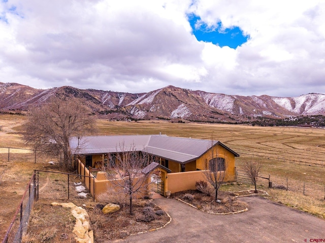 view of front facade with aphalt driveway, a rural view, a mountain view, and fence