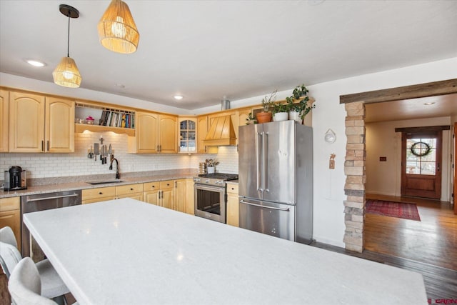 kitchen featuring custom exhaust hood, decorative backsplash, appliances with stainless steel finishes, and a sink