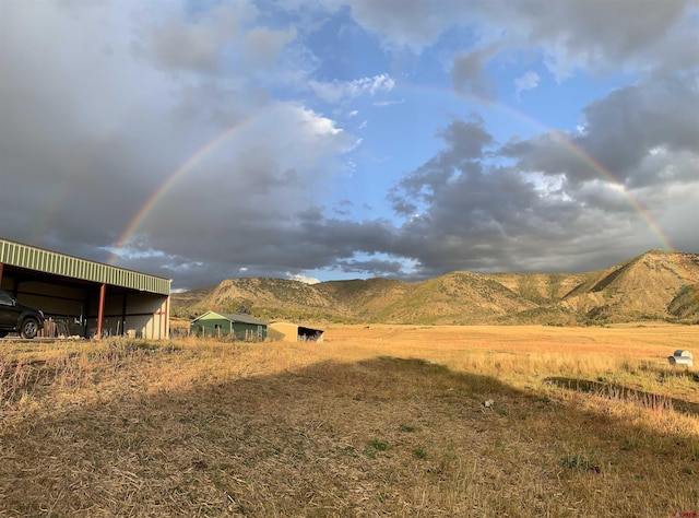 view of yard with a mountain view, a rural view, an outdoor structure, and a pole building