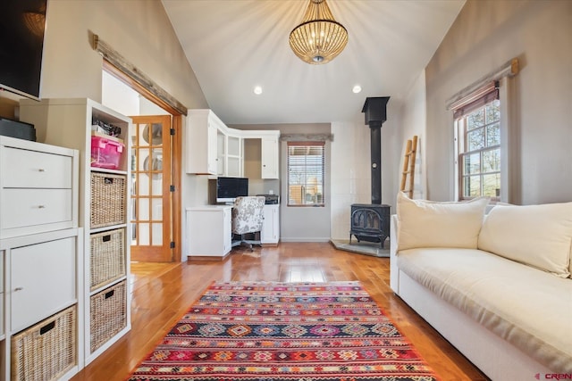 living room featuring vaulted ceiling, a wood stove, recessed lighting, and light wood finished floors