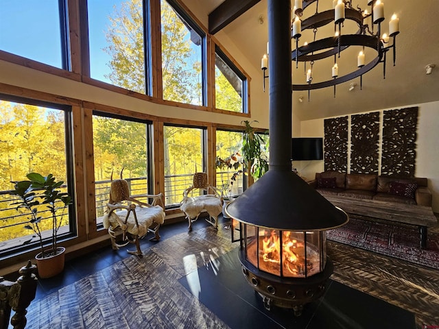 sunroom / solarium featuring a notable chandelier and a wood stove