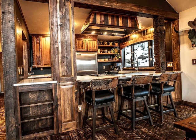 bar with a sink, indoor wet bar, high quality fridge, and decorative columns