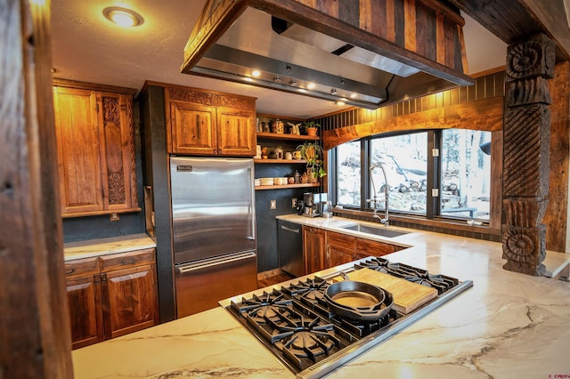 kitchen featuring dishwashing machine, light stone countertops, a sink, cooktop, and built in refrigerator