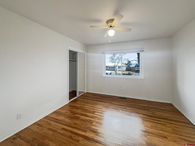 unfurnished bedroom with a closet, visible vents, ceiling fan, and wood finished floors