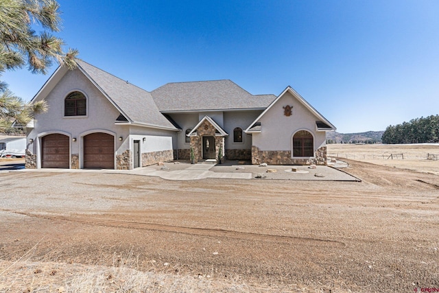 view of front of property featuring stone siding, stucco siding, a garage, and dirt driveway