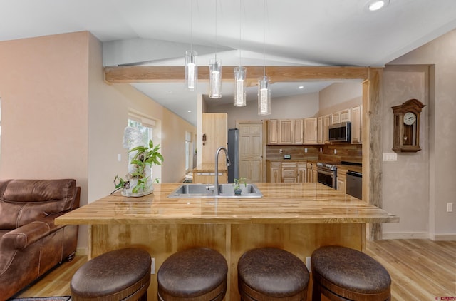 kitchen with vaulted ceiling, a breakfast bar area, appliances with stainless steel finishes, and wood counters