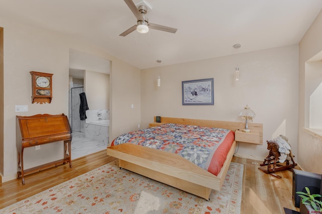 bedroom with connected bathroom, baseboards, and wood finished floors