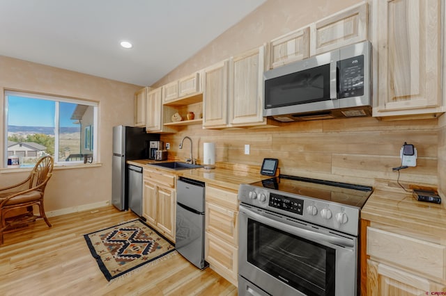 kitchen featuring light brown cabinetry, stainless steel appliances, and a sink