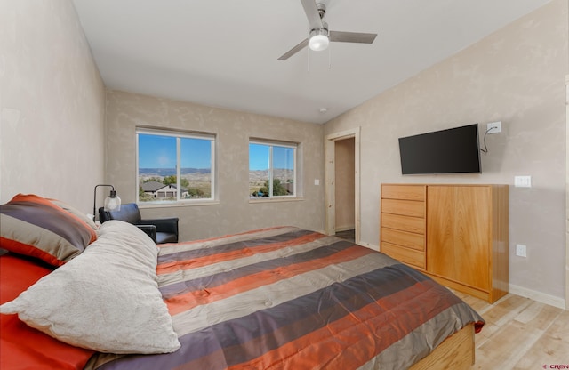 bedroom featuring ceiling fan, baseboards, wood finished floors, and vaulted ceiling