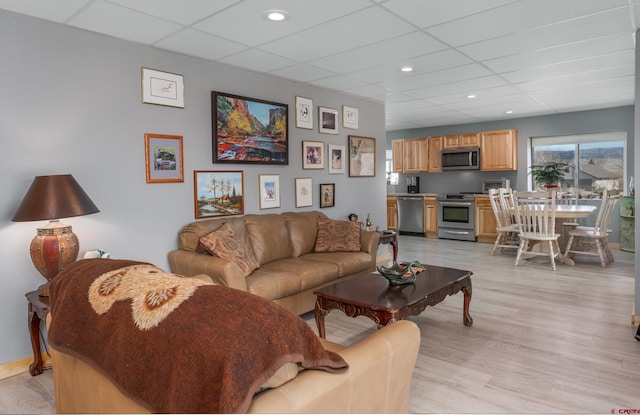 living room with recessed lighting, light wood-type flooring, and a paneled ceiling