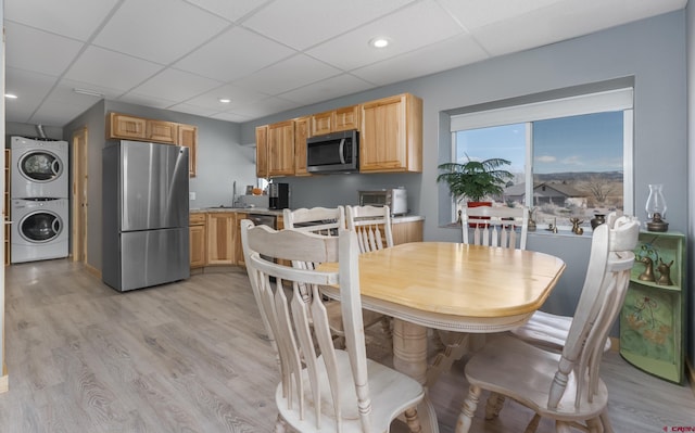 dining room featuring a drop ceiling, light wood-style floors, stacked washer and dryer, and recessed lighting