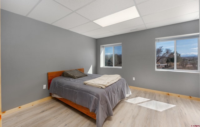 bedroom with a drop ceiling, baseboards, and wood finished floors