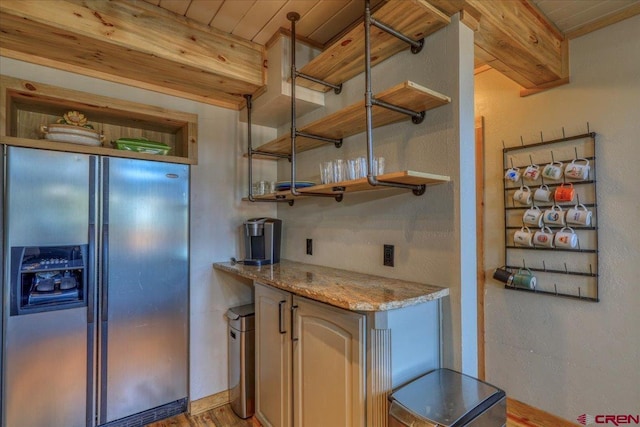 kitchen with light stone counters, open shelves, stainless steel fridge, and wooden ceiling