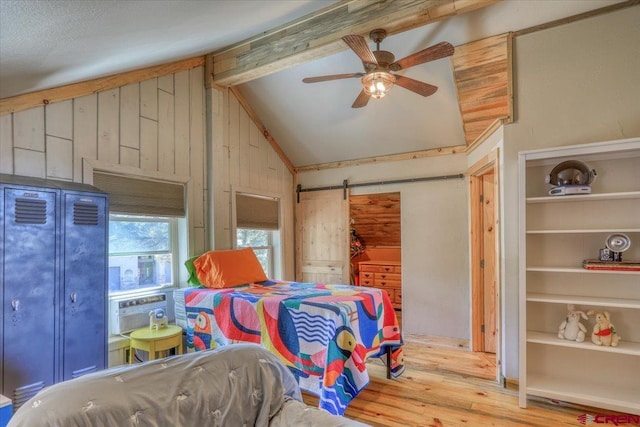 bedroom featuring a barn door, beamed ceiling, wood finished floors, and high vaulted ceiling