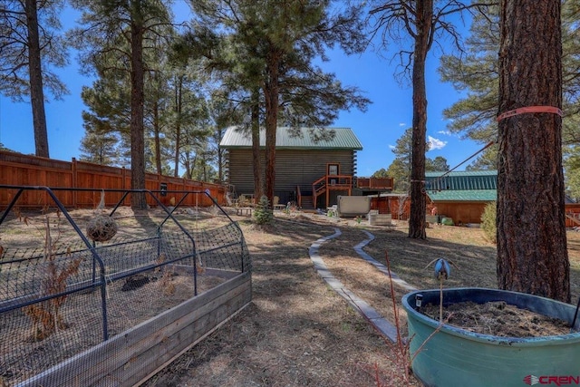 view of yard with a vegetable garden, fence private yard, stairs, and a deck