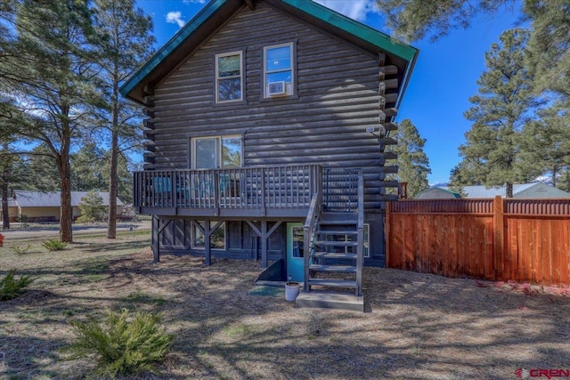 rear view of property featuring a deck, log exterior, and fence