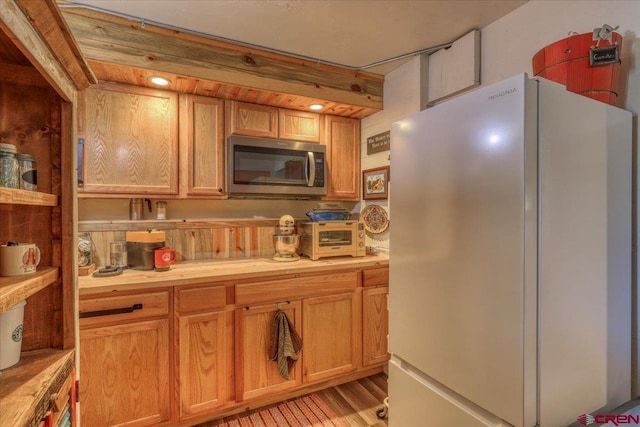 kitchen with a toaster, stainless steel microwave, and freestanding refrigerator