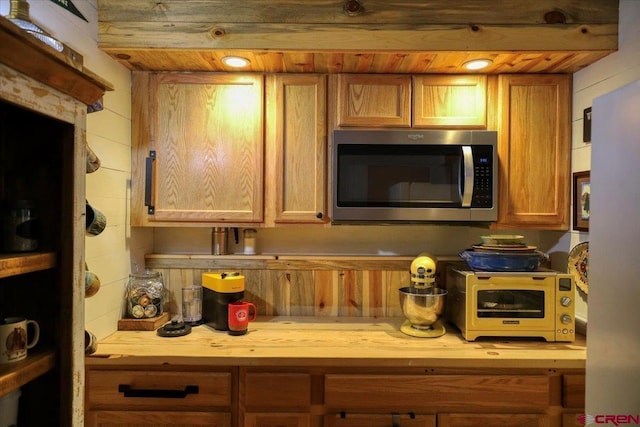 kitchen featuring a toaster, stainless steel microwave, wood ceiling, and wood counters