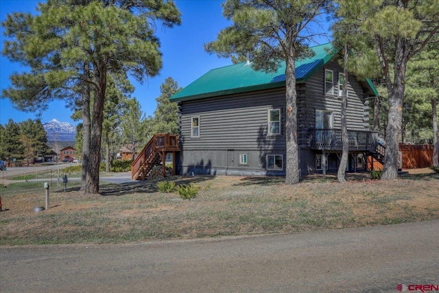 view of side of property featuring a deck, stairway, log siding, and metal roof