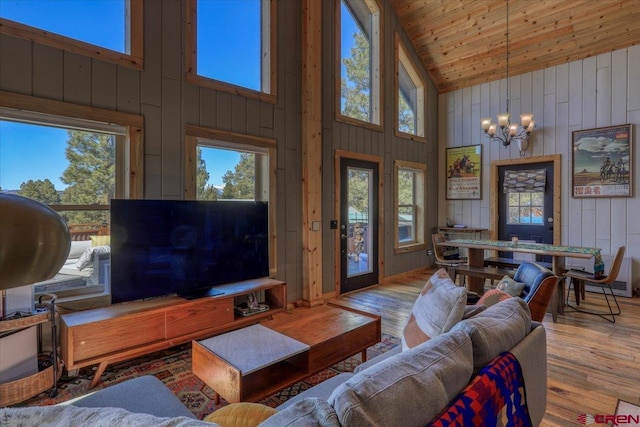 living room featuring an inviting chandelier, wood finished floors, wood ceiling, and a healthy amount of sunlight