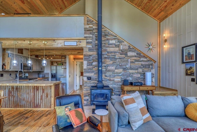 living room with light wood-style flooring, a wood stove, wood ceiling, and high vaulted ceiling