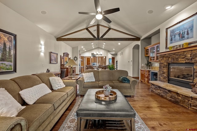 living room featuring dark wood finished floors, lofted ceiling, ceiling fan with notable chandelier, a fireplace, and arched walkways