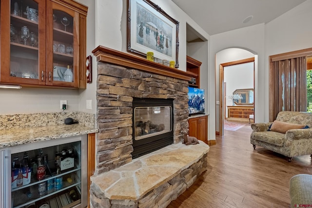 living area featuring a fireplace, beverage cooler, and light wood-style floors