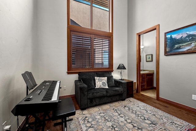 living room with a towering ceiling, baseboards, and wood finished floors