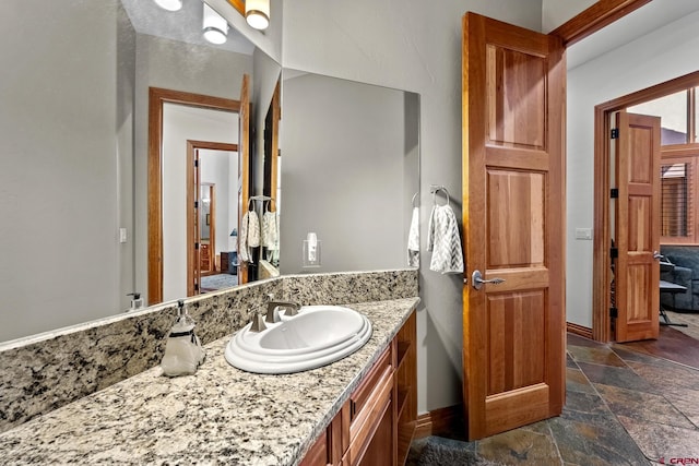 bathroom with vanity, baseboards, and stone tile flooring