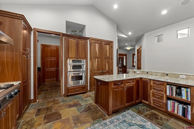 kitchen featuring brown cabinetry, light stone counters, stainless steel appliances, stone tile flooring, and high vaulted ceiling