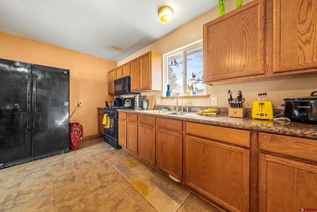 kitchen featuring brown cabinetry, black appliances, dark countertops, and a sink