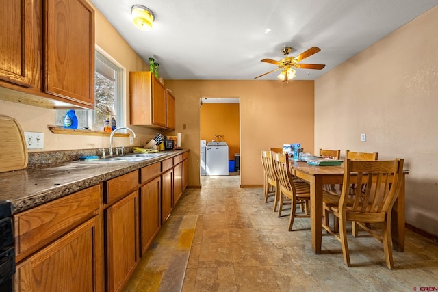 kitchen with brown cabinetry, washer / dryer, ceiling fan, and a sink