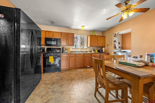 kitchen featuring black appliances, a ceiling fan, brown cabinets, and a sink