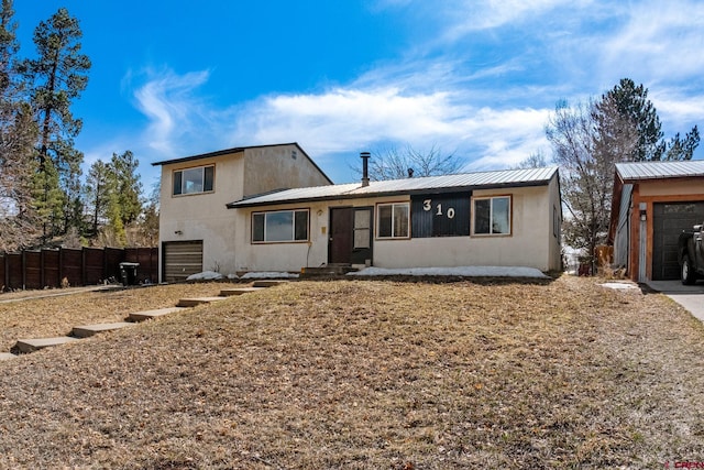 view of front of home with fence, a garage, and metal roof